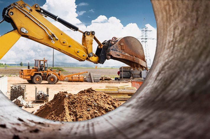 Excavator digs piles. Earthworks for the construction of the foundation. Construction equipment for the device of piles. Preparatory work for grillage. View from a large concrete pipe